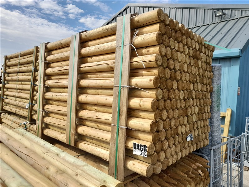 Stacked wooden fence posts bundled outside warehouse