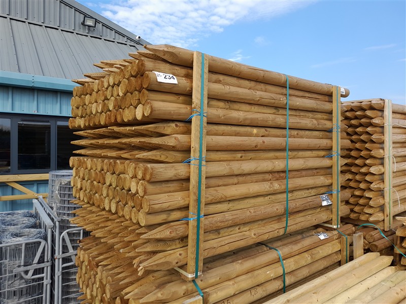 Stacked wooden fence posts outside warehouse