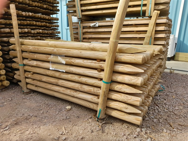 Stacked wooden fence posts with pointed ends outdoors