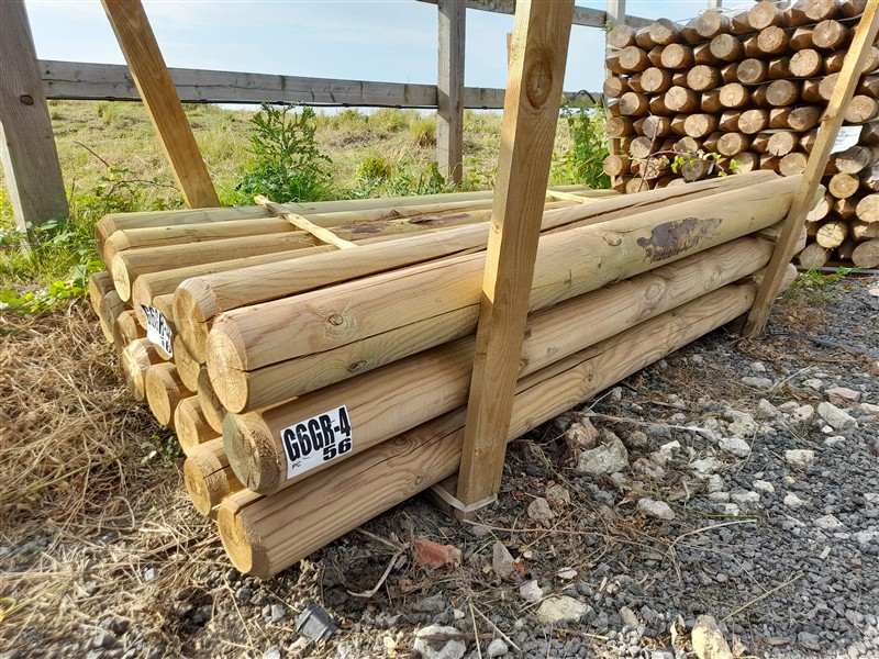 Stacked wooden fence posts under outdoor shelter