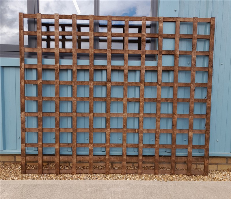 Large wooden garden trellis leaning against blue wall