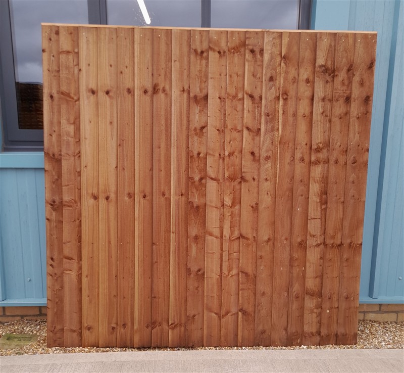 Freestanding stained wooden fence panel against blue building