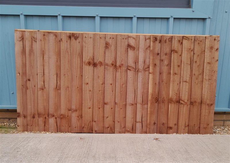 Wooden fence panel leaning against blue shed