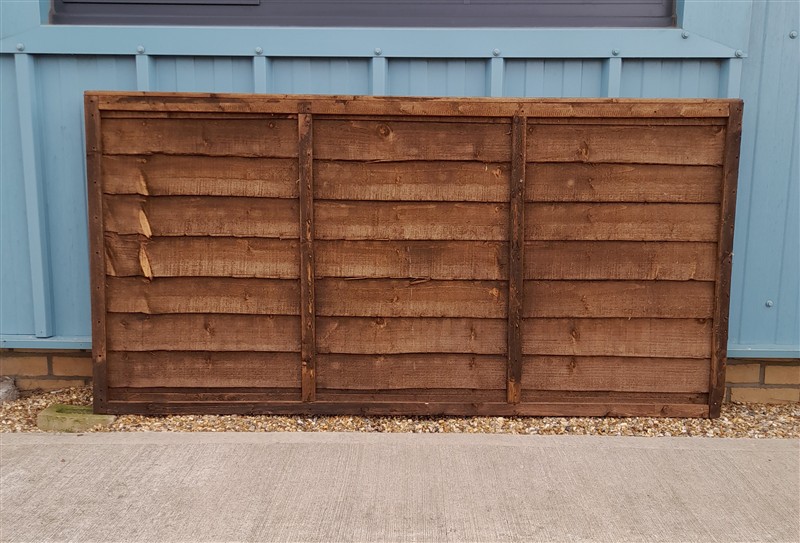 Weathered wooden fence panel leaning against blue wall