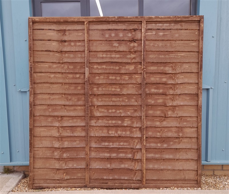 Weathered wooden fence panel against blue building