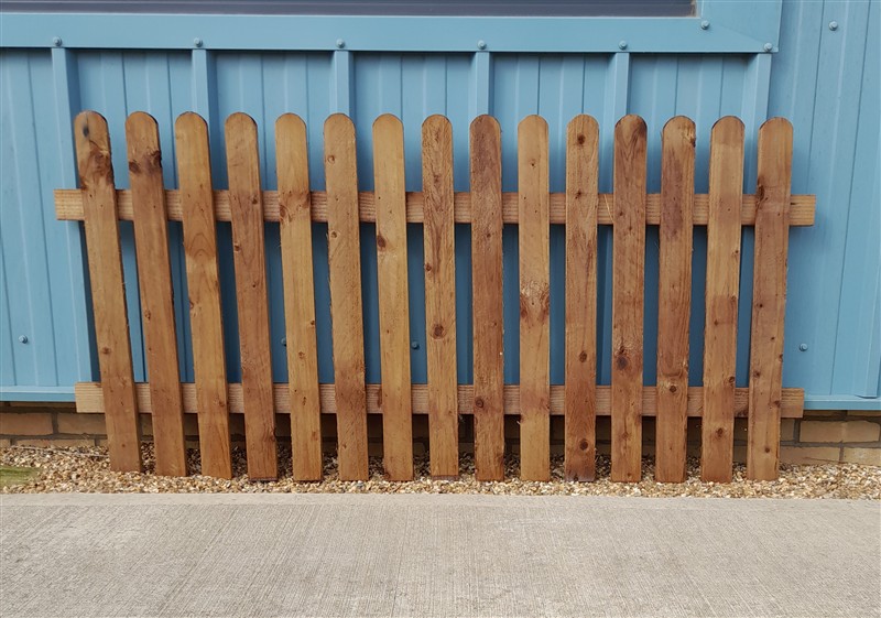 Wooden picket fence panel against blue metal wall