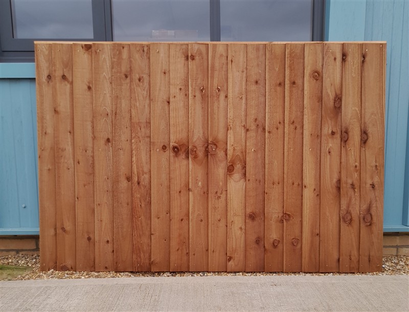 Large vertical wooden fence panel against blue building
