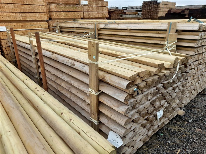 Stacked timber fence posts at a lumber yard